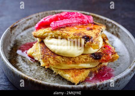 Tiramisù panettone tradizionale italiano arrosto con crema alla vaniglia cagliata e rabarbaro servito come primo piano in una ciotola dal design nordico Foto Stock