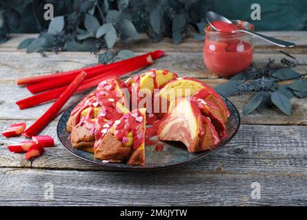 Tradizionale torta di budino al formaggio con cagliata di rabarbaro e crema pasticcera servita come primo piano su un piatto di design con stilo cottage Foto Stock