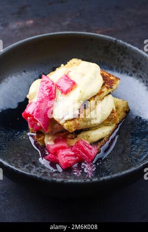 Tiramisù panettone tradizionale italiano arrosto con crema alla vaniglia cagliata e rabarbaro servito come primo piano in una ciotola dal design nordico Foto Stock