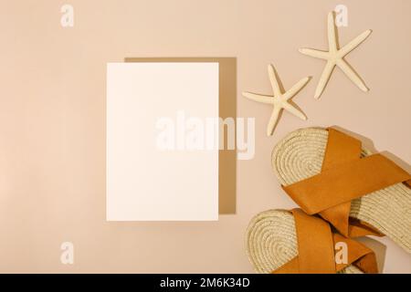 Stelle marine, carte di carta mock up e sandali su sfondo beige spiaggia. Sfondo estivo. Tessile decorativo . Oggetto isolato. Foto Stock