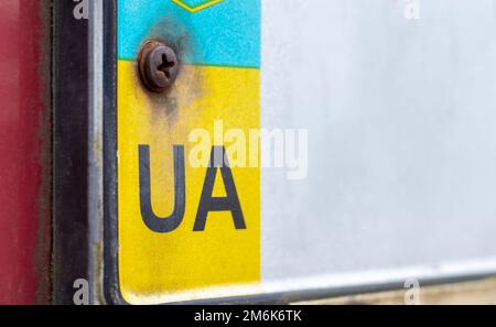 Parte della targa Ucraina sul primo piano del paraurti. Il simbolo della nazionalità sullo sfondo dei colori della Fla Foto Stock