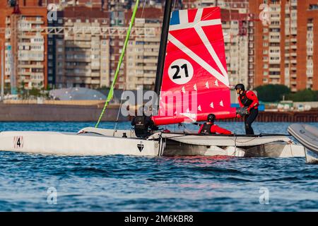 Russia, St. Petersburg, 10 giugno 2022: Il trimarano con i marinai professionisti a bordo galleggiante al tramonto, complesso residenziale Foto Stock