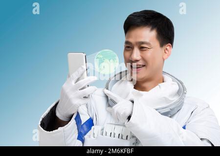 Gli astronauti maschili visualizzano il telefono cellulare e l'ologramma Foto Stock