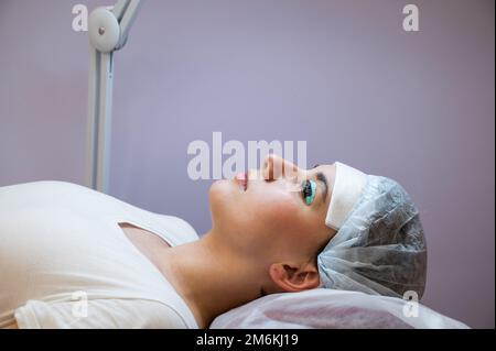 Primo piano ritratto di una donna sulla procedura di laminazione e tintura delle ciglia. Trucco permanente. Foto Stock