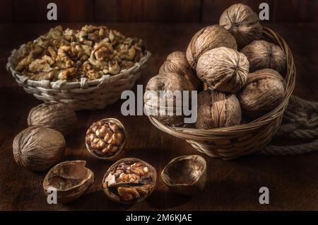 Noci e nocciole in un cesto su uno sfondo di legno scuro Foto Stock