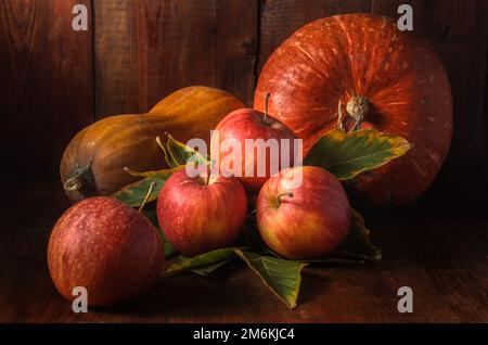 Mele e altri frutti su sfondo di legno scuro in stile rustico Foto Stock