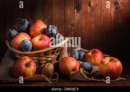 Mele e altri frutti su sfondo di legno scuro in stile rustico Foto Stock