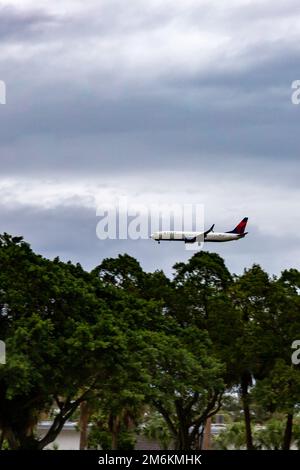 Un jet passeggeri Delta Airlines Boeing 737 vola sopra gli alberi mentre si prepara per l'atterraggio a West Palm Beach, Florida, USA. Foto Stock