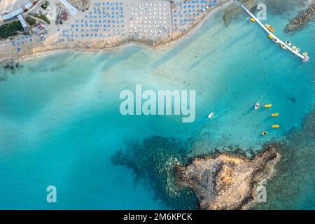 Ombrelloni in fila presso la spiaggia di fichi baie Protaras Cipro. Vacanze estive resort di vacanza. Foto Stock