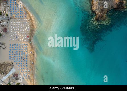 Ombrelloni in fila presso la spiaggia di fichi baie Protaras Cipro. Vacanze estive resort di vacanza. Foto Stock