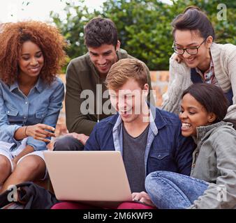 La tecnologia semplifica l'apprendimento. un gruppo di studenti seduti all'aperto mentre si trovano nel campus. Foto Stock