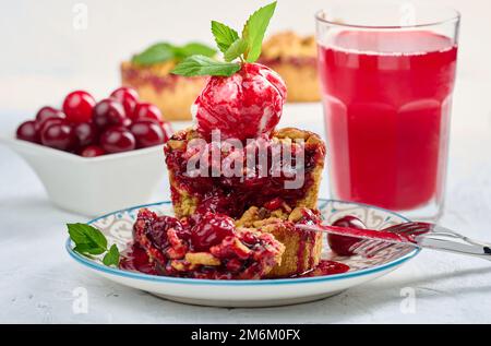 Torta crumble di ciliegie decorata con una paletta di gelato Foto Stock