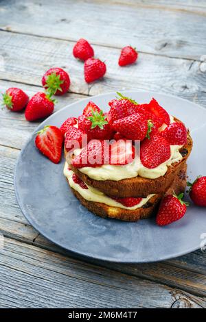 Tiramisù panettone tradizionale italiano arrosto con crema alla vaniglia e fragole servite come primo piano in un piatto di design Foto Stock