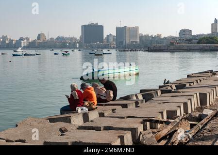 Alessandria, Egitto. Dicembre 1st 2022 persone su blocchi di cemento posizionati come una difesa contro l'aumento dei livelli del mare lungo la Corniche di Alessandria, il Foto Stock