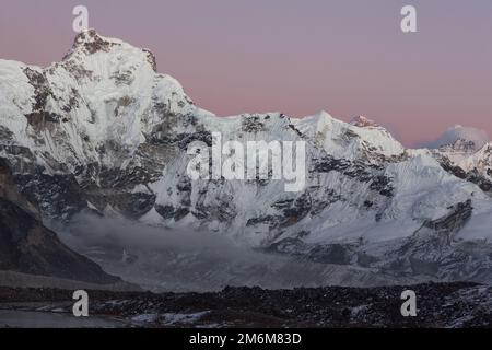 Il tramonto si illumina sulla cima della montagna Cholatse nell'Himalaya, Nepal. Scenario delle Highlands della catena montuosa alla luce del tramonto. Foto Stock