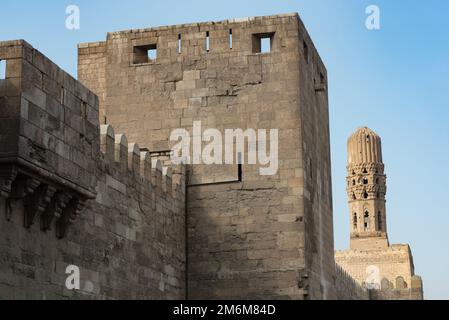 Minareto della Moschea al Hakim con le mura difensive settentrionali fortificate del Cairo islamico, vicino a Bab El Futuh una delle antiche porte degli storici Foto Stock