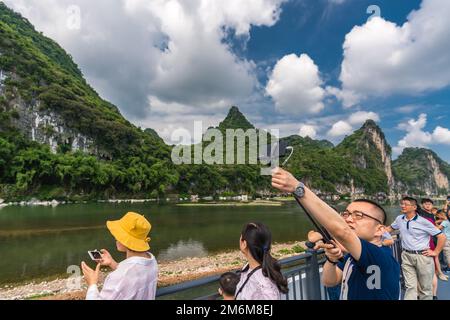 Turisti cinesi che scattano foto al selfie su una barca che naviga sul fiume li Foto Stock