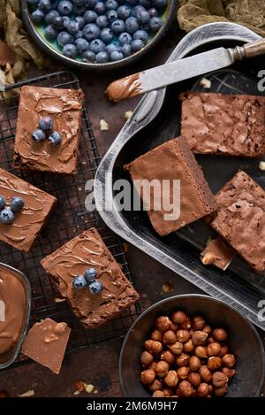 Composizione di quadrati di brownie al cioccolato fatti in casa freschi che fondono cioccolato e mirtilli freschi Foto Stock