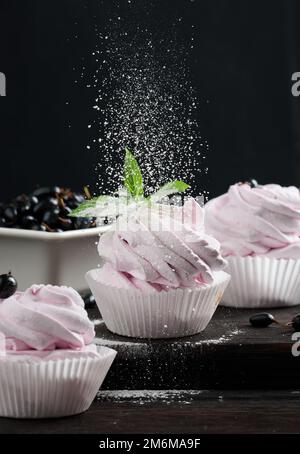 Marshmallows di frutta porzionati in una tazza di carta su un asse di legno nero Foto Stock