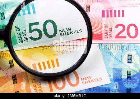 Nuovi shekels israeliani in una lente d'ingrandimento uno sfondo di affari Foto Stock