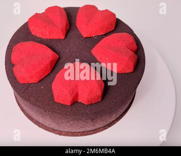 mousse torta al cioccolato marrone con specchio rosso glassa a forma di cuore Foto Stock