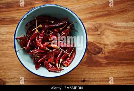 Intensamente piccante. Shot ad angolo alto di peperoncini rossi secchi in una ciotola su un bancone da cucina. Foto Stock