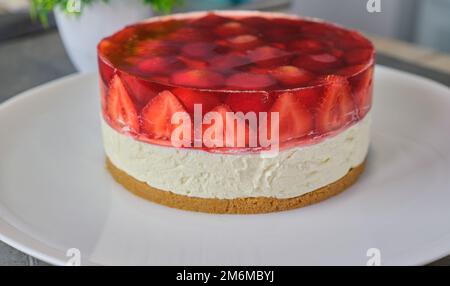 Torta di gelatina di cheesecake alle fragole fredde fatta in casa su piatto bianco Foto Stock