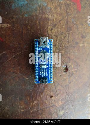 Scheda micro controller Arduino nano utilizzata per applicazioni robotiche, informatiche e di automazione isolate su un tavolo in legno in primo piano Foto Stock