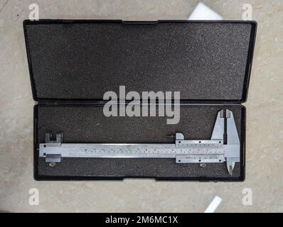 un nuovo strumento di misurazione con calibro a corsoio analogico in acciaio inox utilizzato per misurazioni di precisione in una scatola isolata Foto Stock