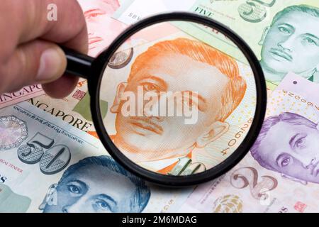Singapore dollaro in una lente d'ingrandimento un background di affari Foto Stock