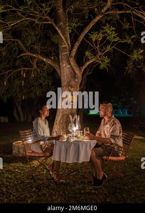 Coppia in safari in Sud Africa, donne asiatiche e uomini europei haveng una cena cespuglio Foto Stock