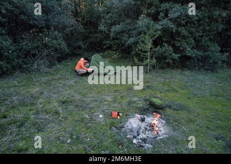 Uomo che porta una bottiglia vicino alla tenda in Sicilia, Parco dell'Etna, Italia Foto Stock