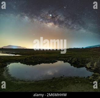 Le stelle del cielo riflettono la luce di notte. La Via Lattea sopra le montagne e lo stagno Mae Prachan Dam e serbatoio, P Foto Stock