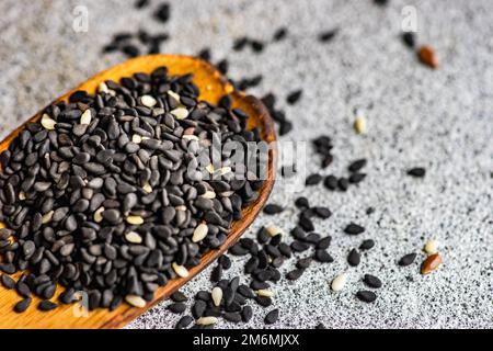 Semi di sesamo nero nel cucchiaio di legno Foto Stock