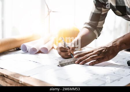 Architetto ingegnere che disegna un edificio o una casa di design con stampa blu, un luogo di lavoro con progetti, matita, goniometro e casco di sicurezza, verde Foto Stock