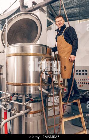 L'uomo lavora presso una fabbrica di birra artigianale. Produzione di birra artigianale. Foto Stock