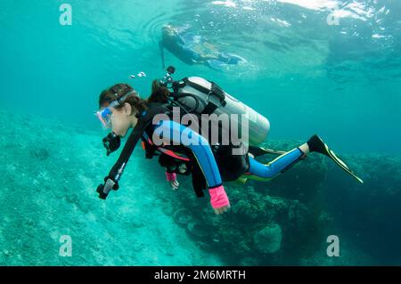 Ragazza di 9 anni che diving con madre snorkeling in background, Post 2 sito di immersione, Menjangan Island, Buleleng, Bali, Indonesia Foto Stock