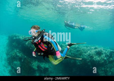 Ragazza di 9 anni che diving con madre snorkeling in background, Post 2 sito di immersione, Menjangan Island, Buleleng, Bali, Indonesia Foto Stock