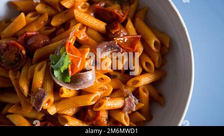 Pasta alla siciliana con acciughe. Pasta con salsa di pomodoro, basilico e olive nere. Foto Stock