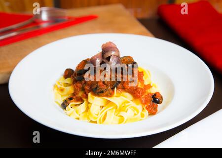 Pasta alla siciliana con acciughe. Pasta con salsa di pomodoro, basilico e olive nere. Foto Stock