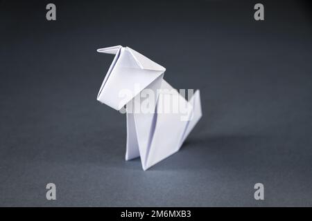 Origami cane di carta bianca isolato su uno sfondo grigio Foto Stock