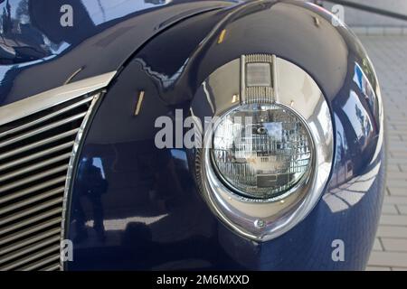 Solo il faro sinistro di un 1940 Mercury mostrato in primo piano con cromatura intorno e parte anteriore del parafango e parte della griglia Foto Stock