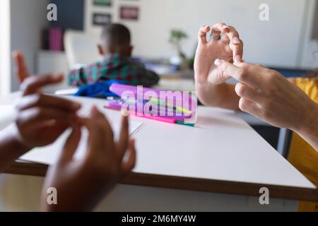 Mani tagliate della giovane insegnante caucasica e della ragazza afro-americana che gestiva durante la lezione Foto Stock