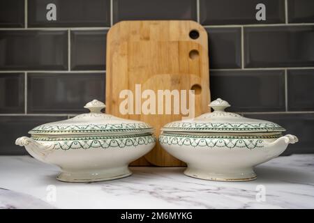 coppia di antiche tuene piene di verdure stagionabili pronte per essere servite nella sala da pranzo Foto Stock