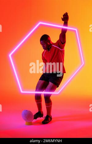 Giocatore di rugby maschile afroamericano con pallina da calcio alzata a mano con esagono illuminato Foto Stock