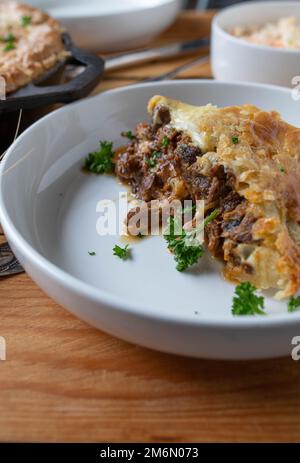 Fetta di bistecca e torta al formaggio su un piatto. Cotto in una padella di ghisa con gambi di manzo Foto Stock