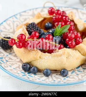 Crostata di frutta con ribes rosso cosparso di zucchero in polvere su un tavolo bianco Foto Stock