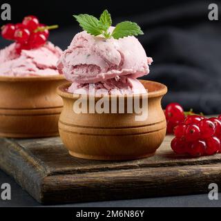 Misurini rosa di pistole con ribes rosso su un tavolo nero. Gelato Foto Stock