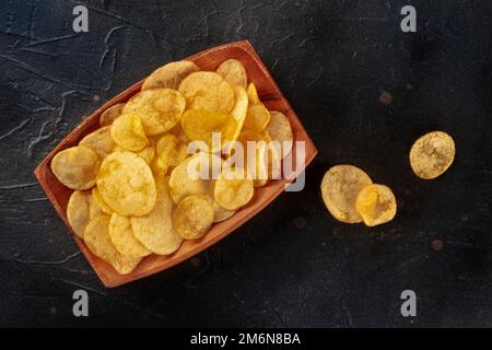 Patatine fritte o patatine fritte, uno spuntino salato, sparato dall'alto sul nero Foto Stock