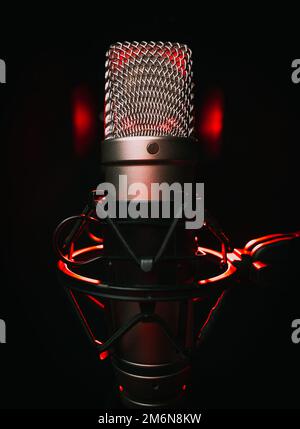Ampio microfono a diaframma per podcast su sfondo nero con luce rossa Foto Stock
